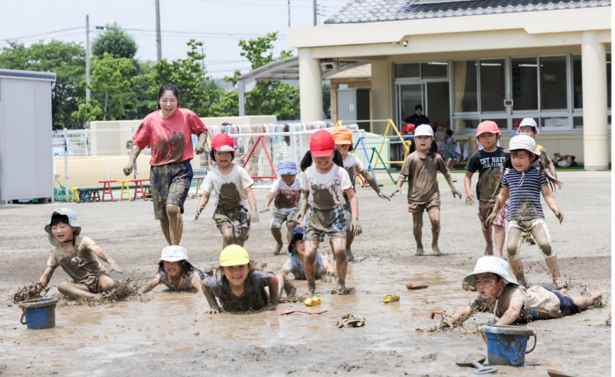 どろで遊ぶ子どもと先生